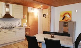 Modern kitchen with a dining area and a wooden table. The walls are bright, and there are decorative accents.
