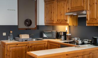A modern kitchen with wooden cabinets and a simple countertop. There are various kitchen appliances and utensils on the countertop.
