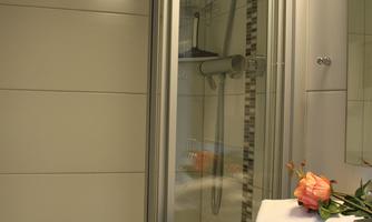 A modern bathroom with a shower and a sink. On the sink, there is a towel and a flower as decoration.