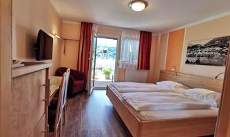 A cozy room with a double bed and a TV. The room has large windows and access to the balcony.