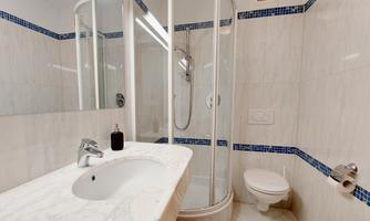 A modern bathroom with a shower and a bright marble sink. The walls are in soft, light colors.