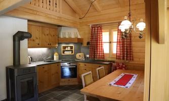 A cozy kitchen in a wooden house with modern appliances. Red checked curtains and a rustic table give the room an inviting character.