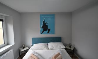 A modern bedroom with a cozy bed and colorful towels. An artistic poster hangs on the wall.