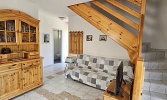 A cozy living space with a wooden dresser and a sofa. The staircase on the right side leads upstairs.