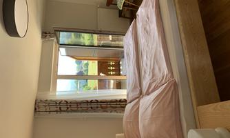 A cozy bedroom with a double bed and pink bed linen. The balcony offers a view of the surrounding landscape.