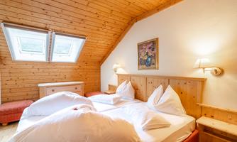A cozy bedroom with wooden-paneled walls. Two beds with white pillows and a beautiful mural.
