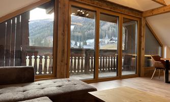 A cozy living space with a view of the mountains. Large windows with wooden elements provide plenty of light and an inviting atmosphere.