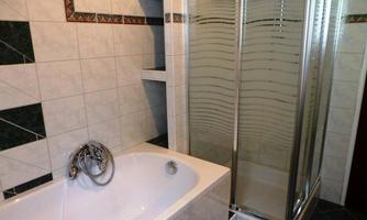 A modern bathroom with a bathtub and a shower. The walls are designed with light tiles and decorative accents.