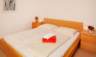 A cozy bedroom with a large wooden bed and fresh flowers on the nightstands. The walls are bright, and the room feels inviting and friendly.