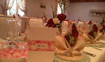 An elegantly set table with flowers and decorated napkins. The menu is in the center, surrounded by glasses and beautiful dishes.
