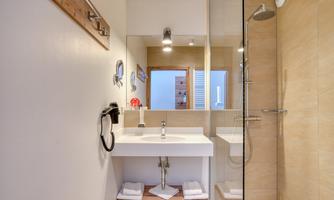 A modern bathroom with a shower and a sleek sink. The walls are bright and the space feels clean and inviting.