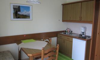 A cozy kitchenette with a table and chairs. The walls are light, and a picture hangs decoratively above the table.
