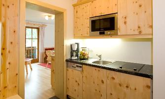 A modern kitchen with wooden cabinets and a dark floor. It is well-equipped and offers an inviting view of the living area.
