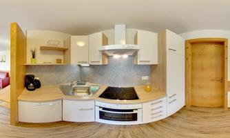 A modern kitchen with white furniture and wooden accents. The equipment includes a stove, a sink, and a refrigerator.