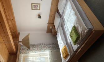 A cozy bedroom with two single beds and light bedding. The walls are painted in soft colors and a window provides daylight.