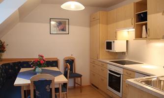 A modern kitchen with light wooden furniture and a cozy dining area. The room is well-lit and inviting.