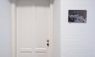 A white door with a golden doorknob. Next to the door is a sign that reads "DO NOT TOUCH".