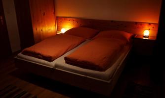 A cozy bedroom with a double bed and orange bedding. Soft light creates a pleasant atmosphere.