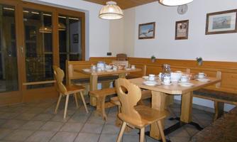 A cozy dining area with wooden tables and chairs. The room has a warm atmosphere with rustic decor.