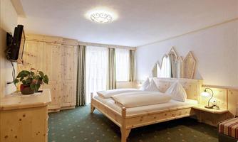 A cozy bedroom with a double bed and wooden furniture.  
Soft carpets and large windows create an inviting atmosphere.
