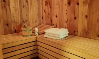 A cozy sauna with wooden paneling and benches. Towels are laid on the bench, and a small basket is ready.