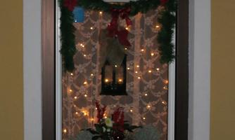 A festively decorated window with lights and pine greenery. In the foreground is a planter box with Christmas decorations.