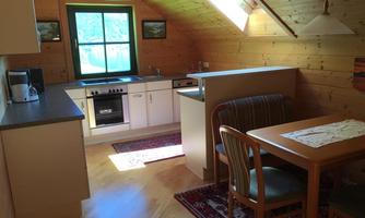 A cozy kitchen with a dining table and chairs. Bright wooden panels create a warm and inviting atmosphere.