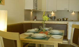 An inviting dining area with a table set for a meal. In the background, you can see a modern kitchen.