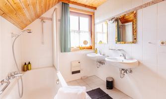 A modern bathroom with a shower and bathtub. Bright tiles and wooden ceilings create an inviting atmosphere.