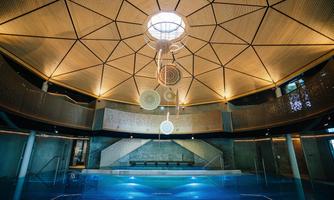 A modern interior with a dome-shaped ceiling and a large body of water. The design is elegant and stylish with wooden and glass elements.