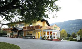 A cozy house with a reception area and a shop. In the background, mountains and trees can be seen.