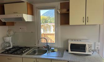 A modern kitchen with a window that offers a view of nature. It is equipped with a sink, stove, microwave, and other kitchen utensils.