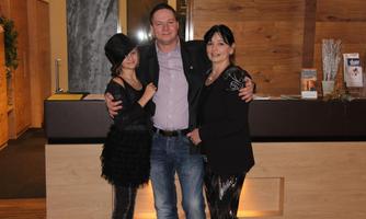 A group of three people is standing in a modernly designed room. In the background, there is a wooden reception desk.