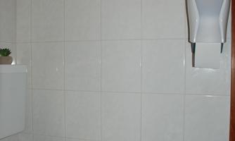 A clean toilet in a bright bathroom. The walls are equipped with white tiles.