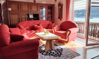 A cozy living room with red sofas and a table.  
Large windows with a view of the landscape provide plenty of natural light.