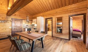 A cozy wooden apartment with a modern dining area and open kitchen. The space is bright and inviting, with a warm, rustic ambiance.