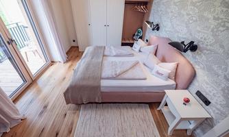 A cozy bedroom with a comfortable bed and modern furniture. Large windows provide plenty of daylight and an inviting atmosphere.
