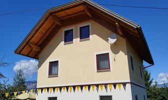 A beautiful house with a gable roof and yellow facade. Fluttering ribbons adorn the front.