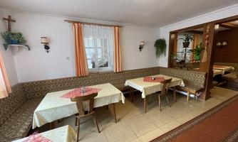 A cozy restaurant with several tables and an inviting atmosphere. The walls are light and decorated with plants, which makes the space feel friendly.