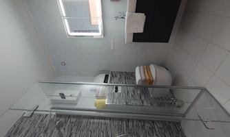 A modern bathroom with a glass shower and an elegant vanity. The walls are designed with a decorative stone pattern and there are fresh towels.