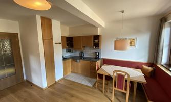 A modern kitchen with a dining area in warm wood tones. The space is bright and inviting with a cozy table and a bench.