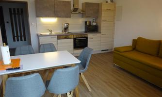 A modern kitchen with a dining area and a cozy sofa. The room is bright and cheerfully furnished.