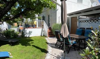 A well-maintained garden with lawn areas and a cozy seating area. In the background, the Casa Nonna with the terrace is visible.