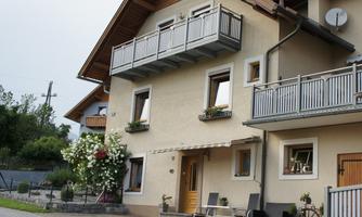 A lovely house with a balcony and blossoming plants. The surroundings are calm and inviting.