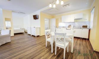 A modern and bright living room with a dining area. The walls are painted in warm shades of yellow, and the floor is made of wood.