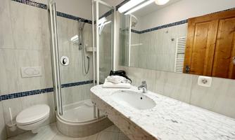 A modern bathroom with a shower cubicle and an elegant marble shelf. It is bright and functionally furnished.
