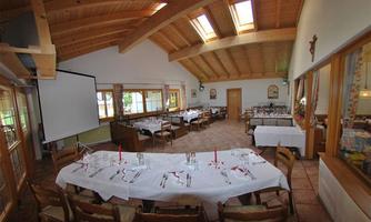 An elegant restaurant with wooden beam ceiling and large windows. The tables are festively set and invite you to linger.