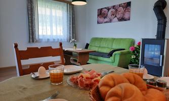 A cozy breakfast table with rolls, sausage, and an egg. In the background, there is a green sofa and a fireplace.