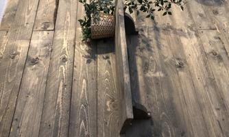 A simple wooden wall shelf on a rustic wall. It is decorated with a pot of plants.