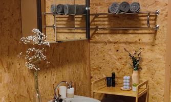 A modern bathroom with a wooden wall and a sink. Towels and small decorations are carefully arranged.